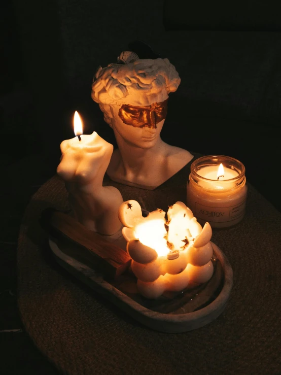 candles in front of a statue with angels on it