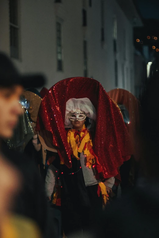 a masked person dressed in red, yellow and white on the street