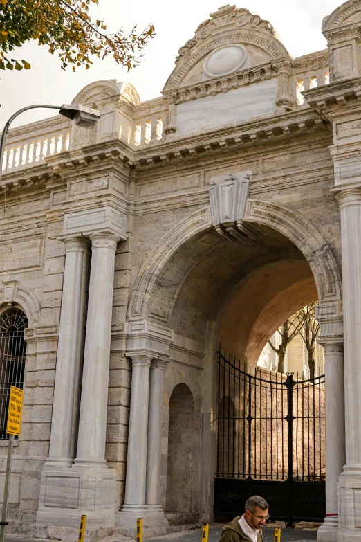 a man is sitting outside an ornate, stone archway