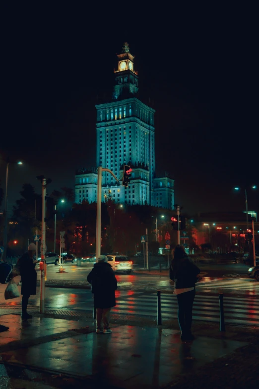 people crossing the street in front of a tall building with a clock on top