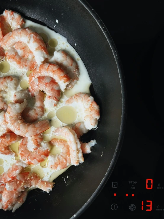a frying pan with shrimp and a sauce