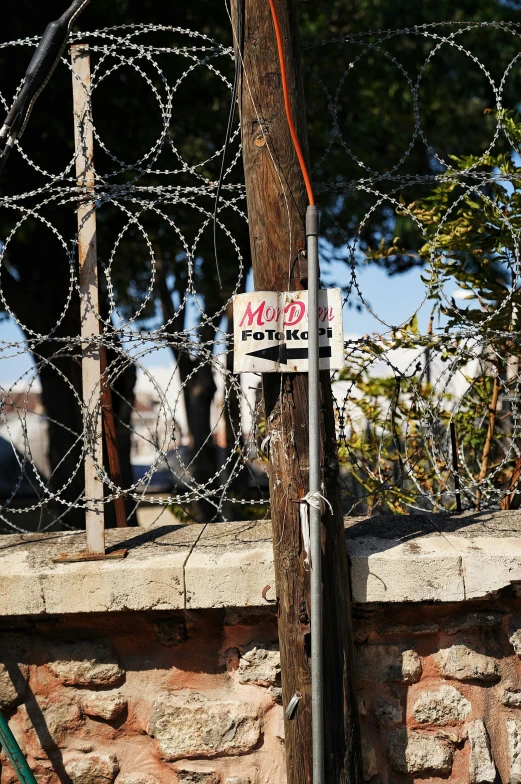 there is a sign and a fence by the rock wall