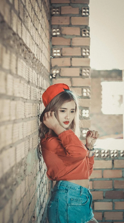 girl with red cap standing against a brick wall