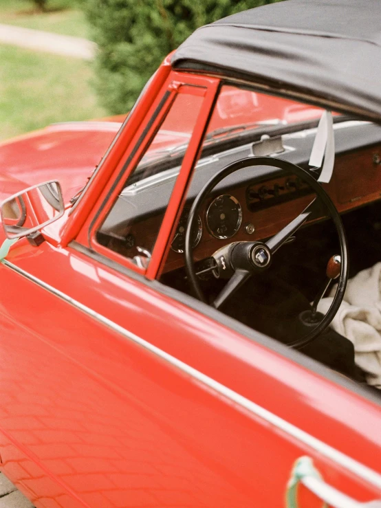 an old style red car with a steering wheel