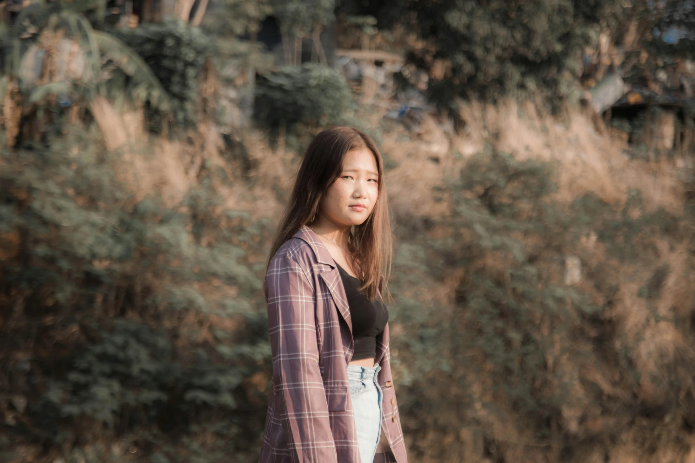 the young asian woman is posing in front of a green field