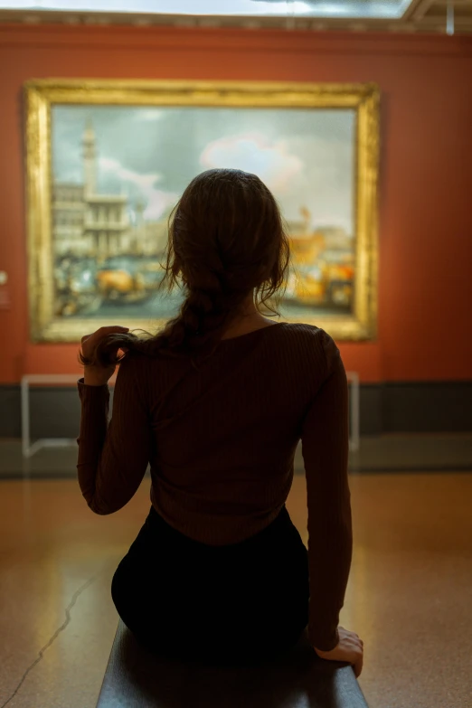 a woman sitting on the floor next to a painting