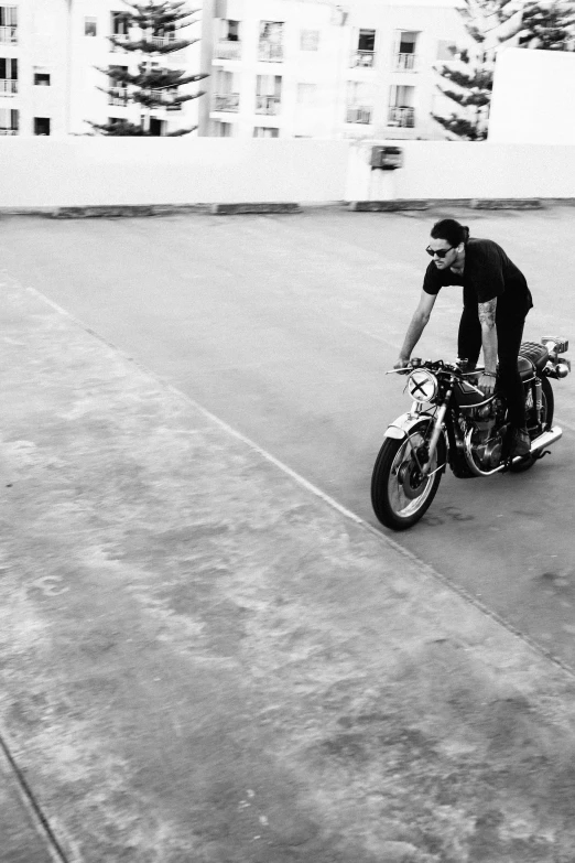 a man riding on the back of a motorcycle on a sidewalk