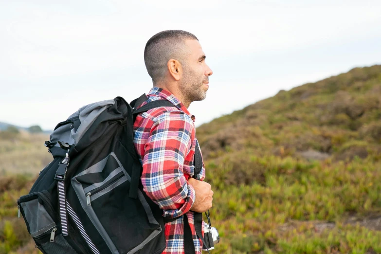 a man stands outside on the grass and hills