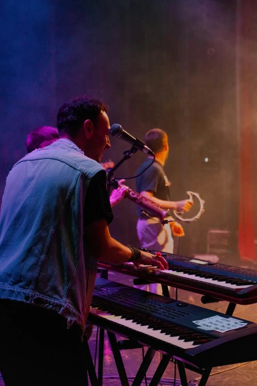 two men are playing keyboards in front of a microphone