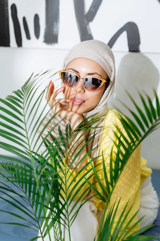 a woman wearing a headscarf and holding her hand in front of a plant