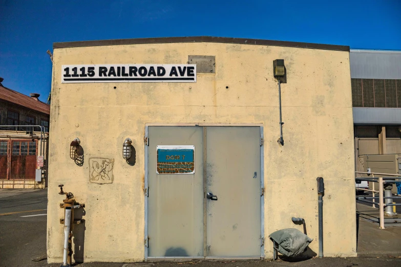 an empty yellow building has a blue sign that reads 1035 railroad avenue