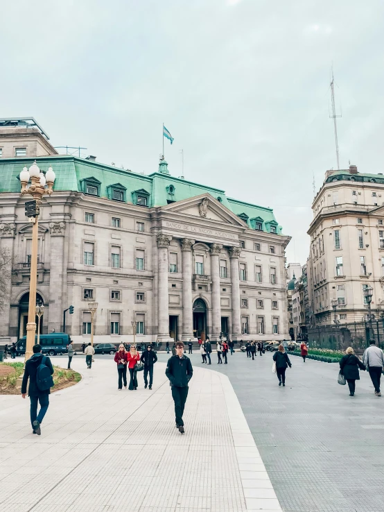 people are walking on a stone walkway leading to a building with green roofs