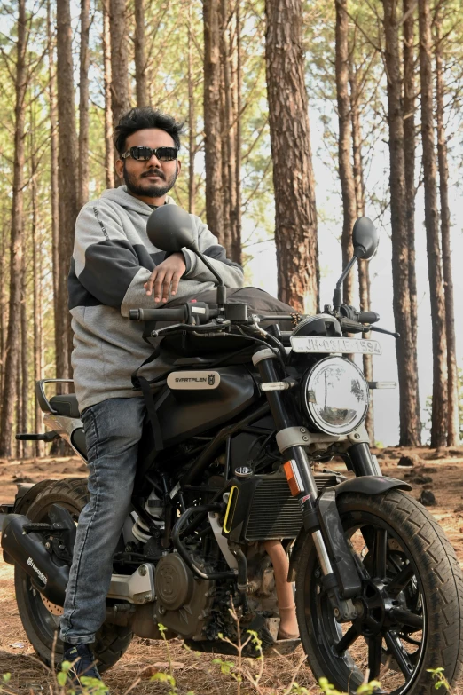 a man sitting on a motorcycle in the woods