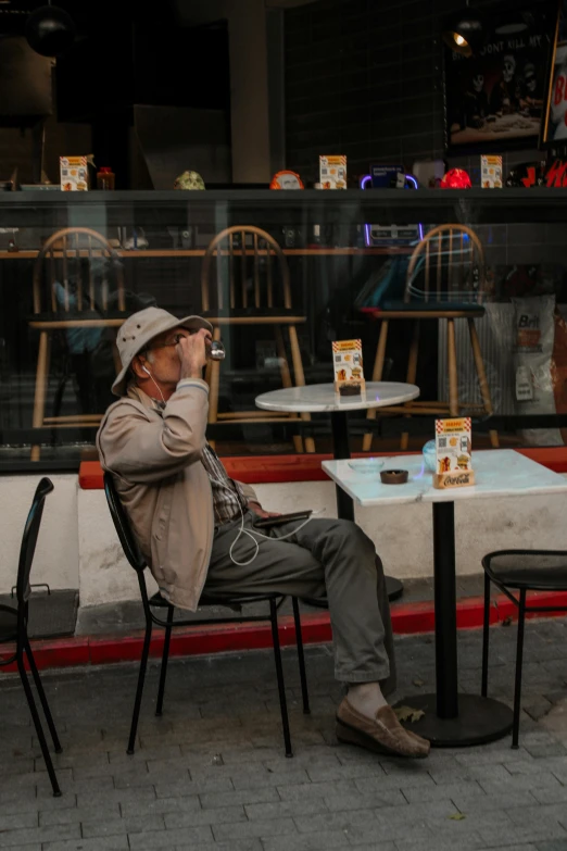 a man sits on a chair at a table in front of a building