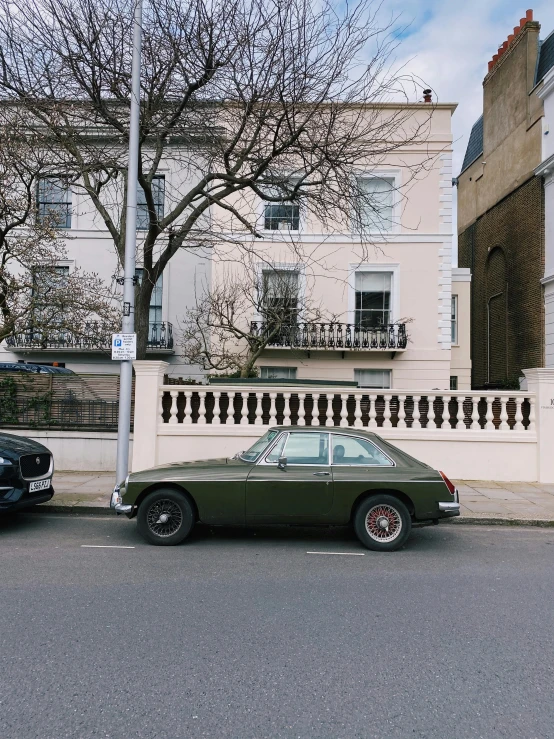 two old cars parked outside an apartment building