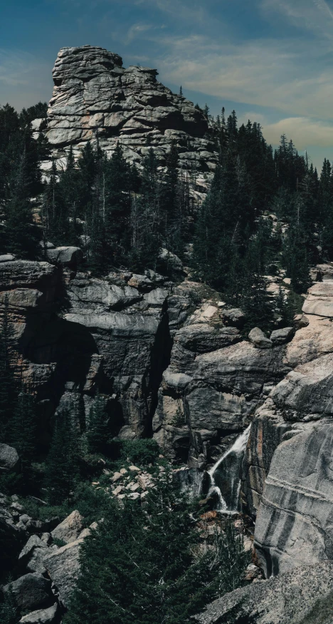 rocky outcropping with a waterfall on it, viewed from the top of a tall mountain