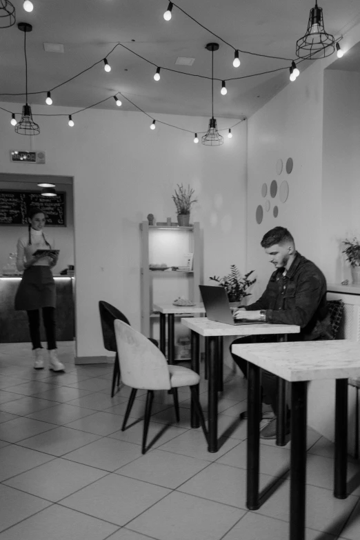 black and white pograph of a man sitting at a desk on his laptop