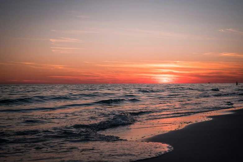 the sun setting over the ocean next to the beach