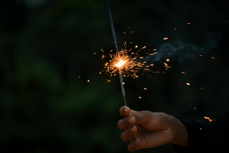 a hand holding a sparkler in the dark