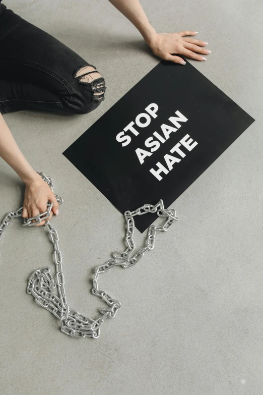 the girl is kneeling down to hold a sign that says stop asian hate