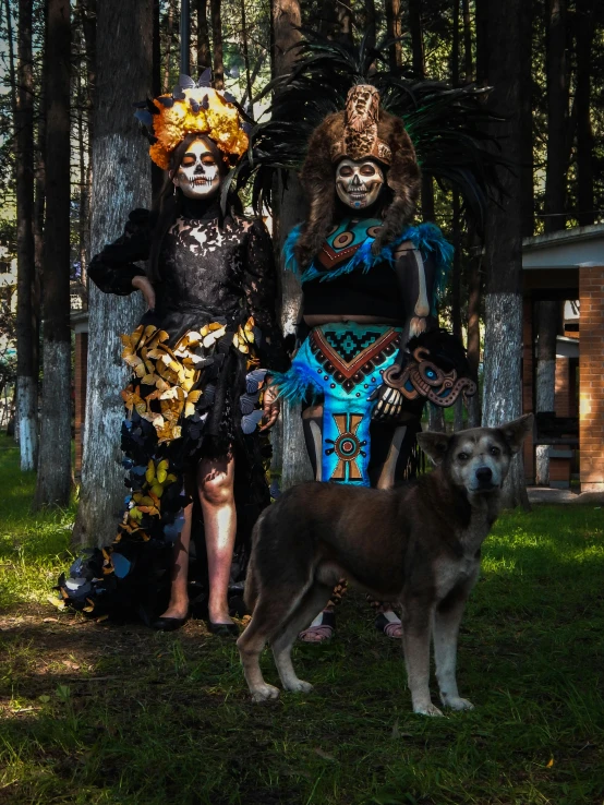 two adults with halloween makeup standing next to a dog