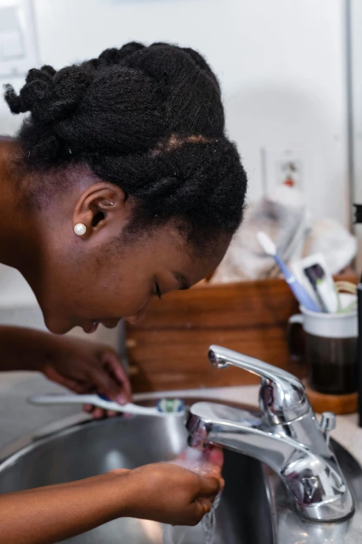 a woman is fixing the water from a kitchen faucet