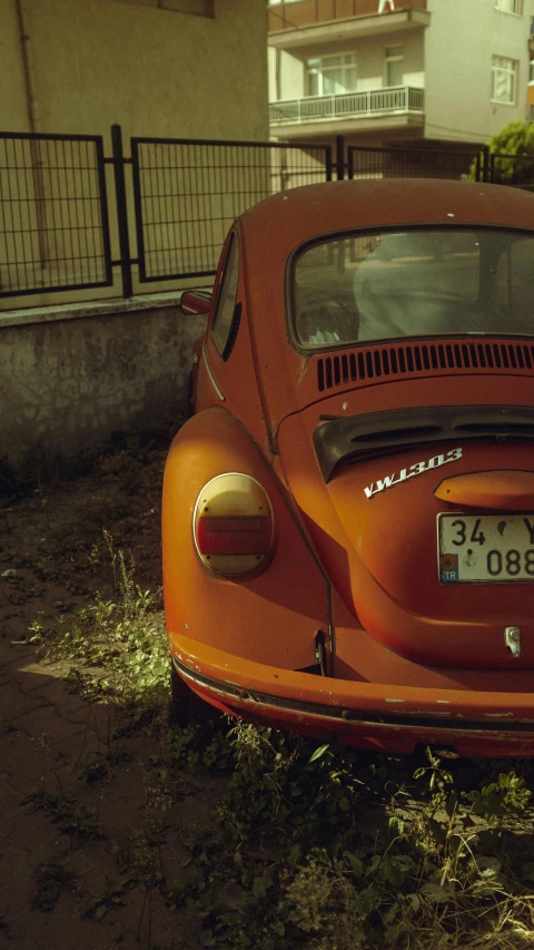 an old, red beetle sits parked in the yard