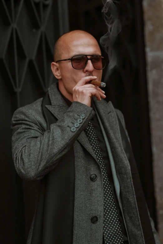 a bald man with sunglasses is smoking a cigarette