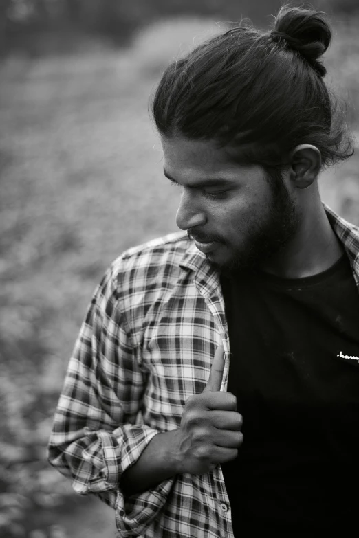 a young man with an up - do is standing in a field