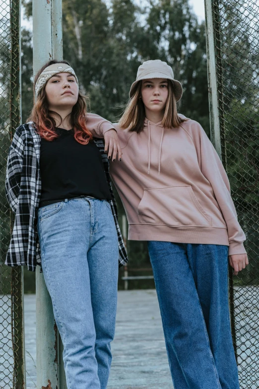 two female s standing by a fence on the ground