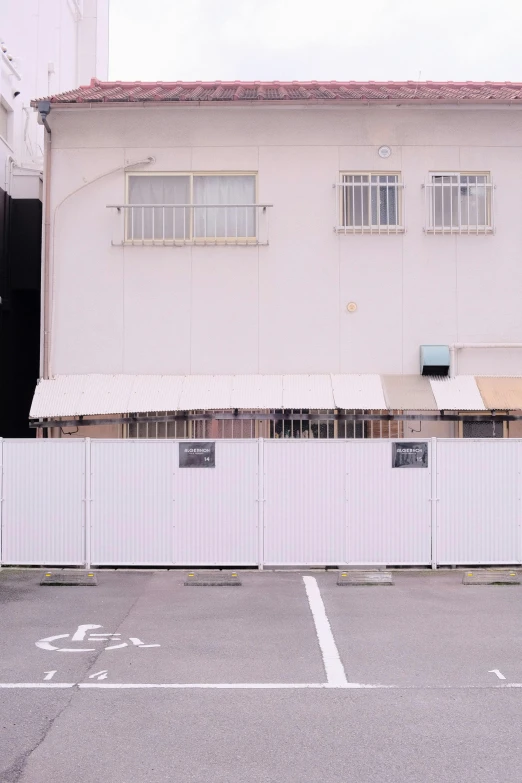 white fence by the building has a bicycle parked in front