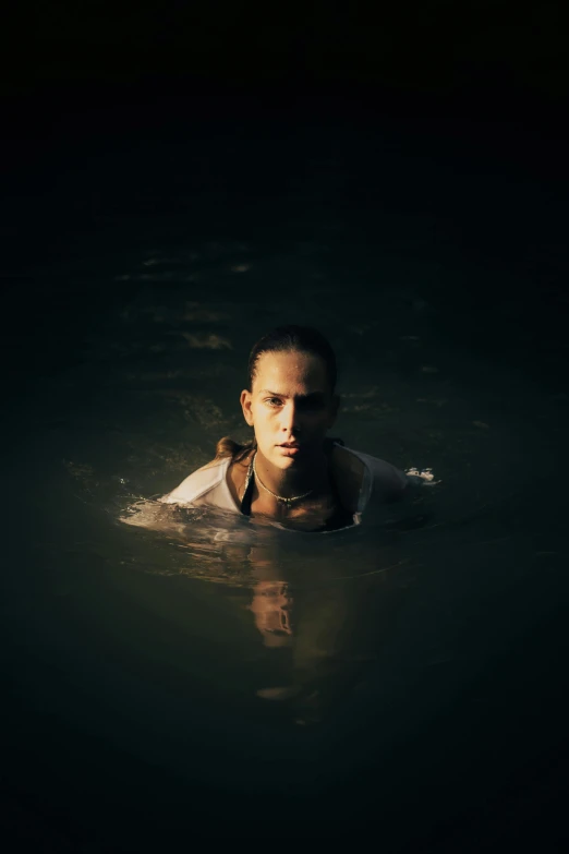 woman with frisbee swimming in dark body of water