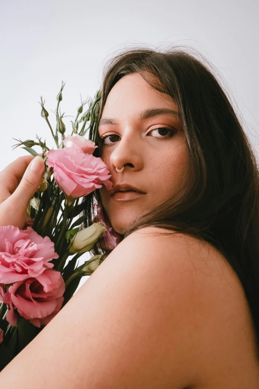 a woman smelling a large bunch of pink flowers