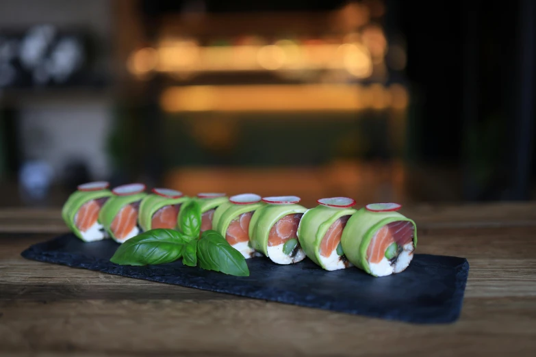 a group of sushi rolls with lettuce on a black slate board