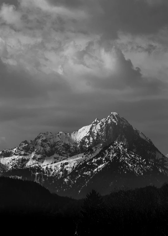 a large mountain covered in snow with clouds