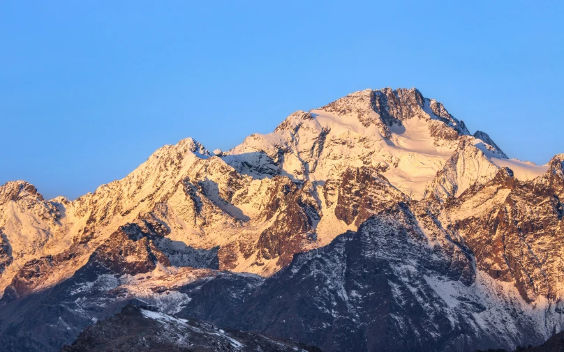 snow covered mountains at dusk with the moon in the sky