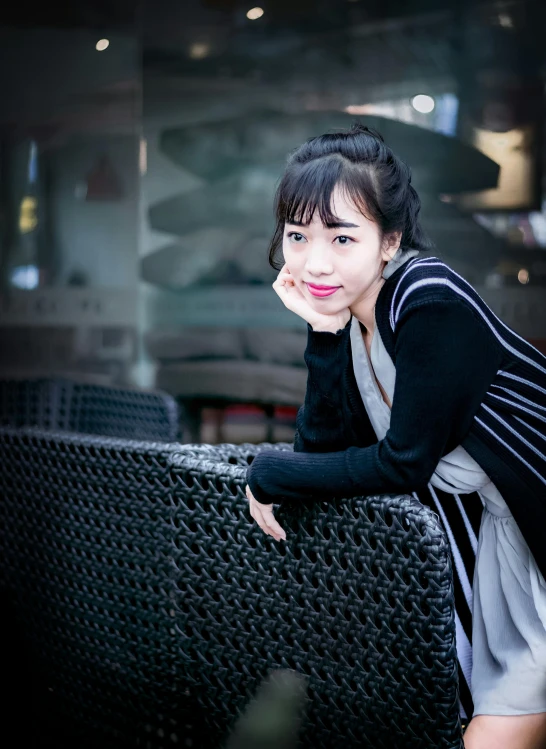 an asian woman is leaning on the arm of a bench