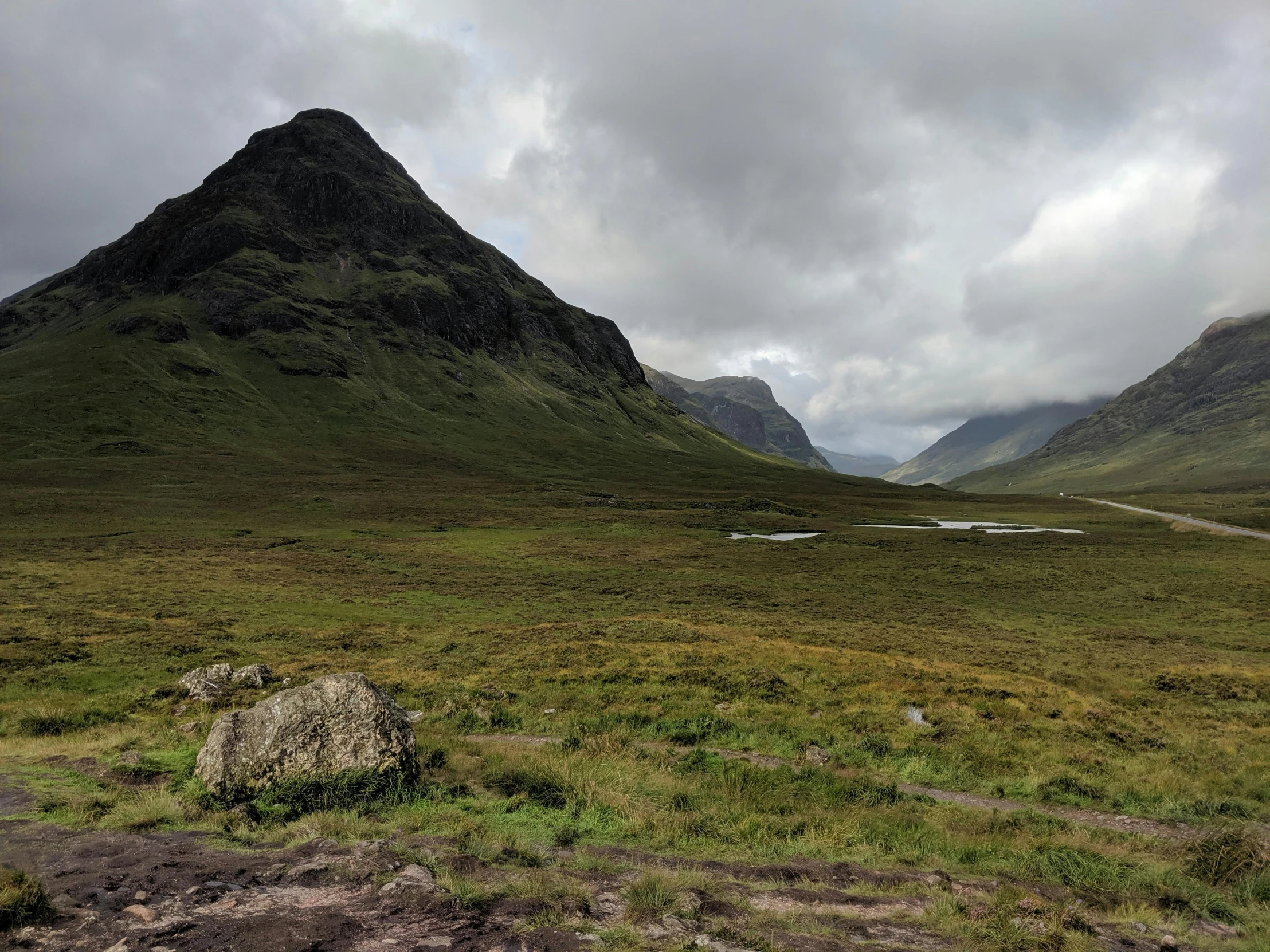 a grassy meadow with mountains on either side