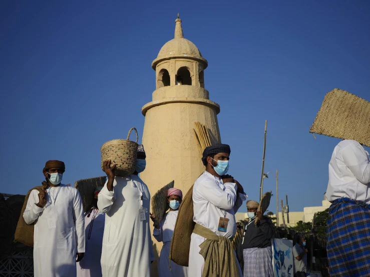 people with surgical masks and weapons stand in front of a structure with a clock