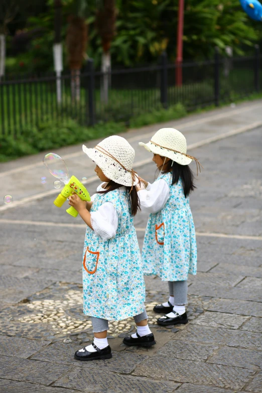 two little girls playing with bubbles on a street