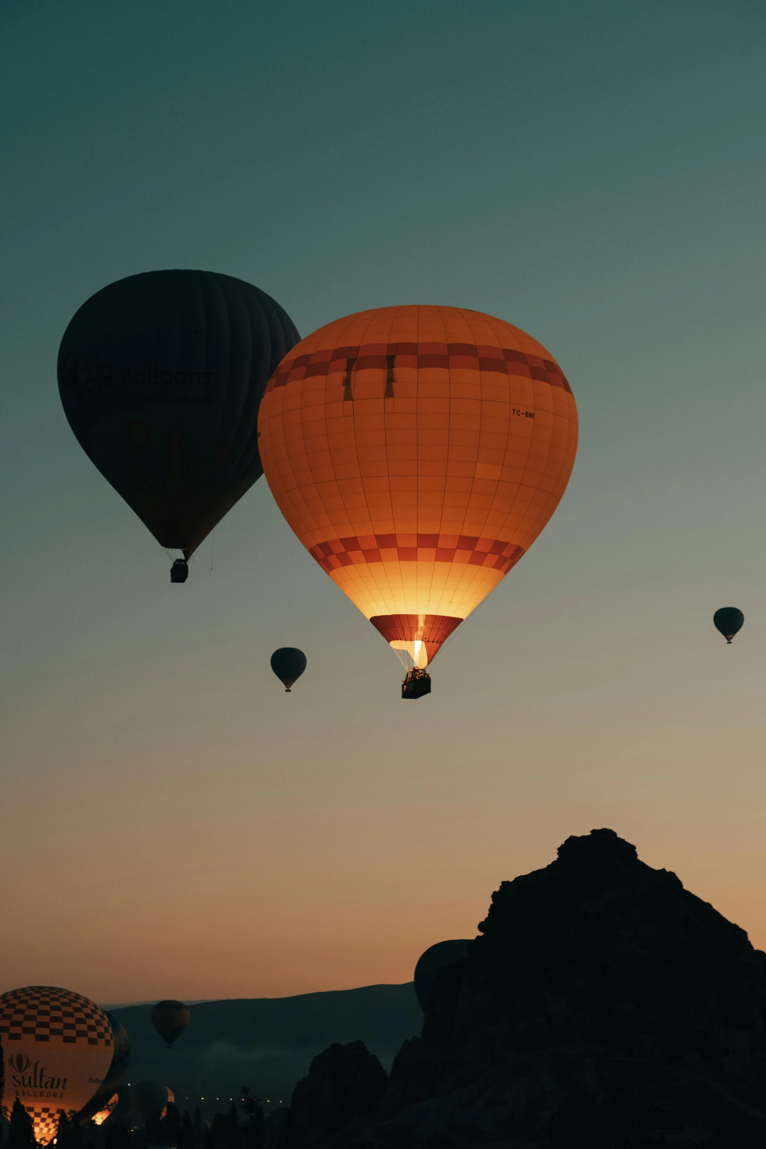 several  air balloons lit up over the sky