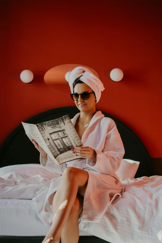 a person in a robe and sunglasses sitting on a bed