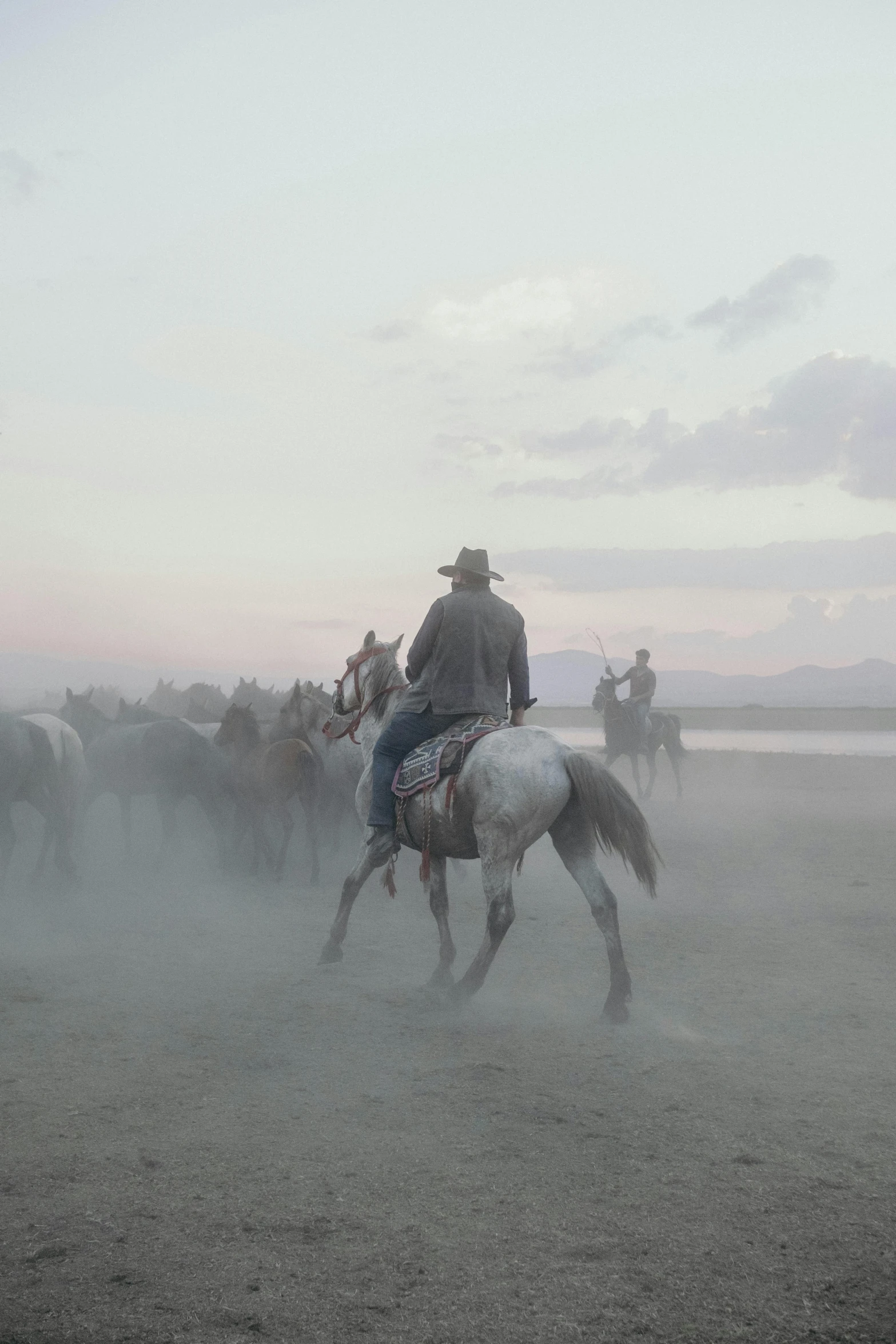 a group of cowboys riding horses through the dust