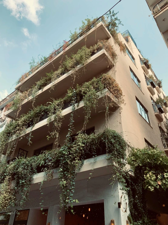 an apartment building covered in green plants near street signs