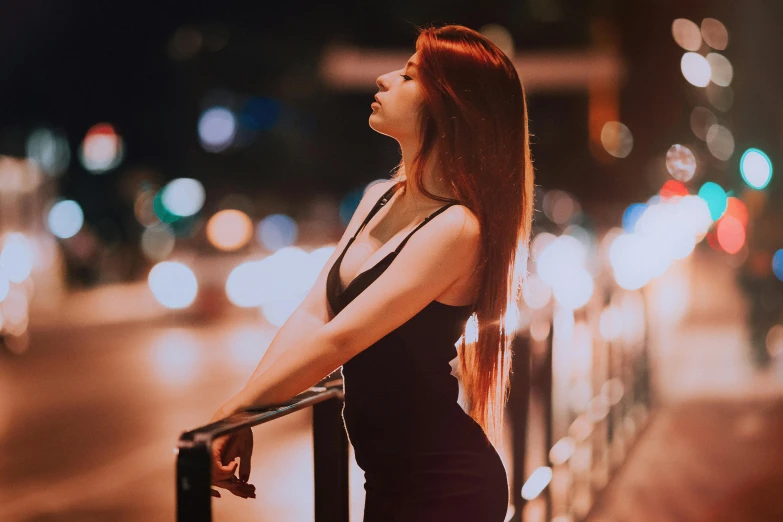 a woman standing near a railing overlooking a city street