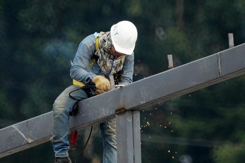a man with hardhat on a beam working