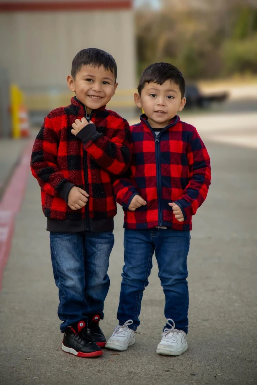 two boys, one in plaid jacket and blue jeans standing side by side