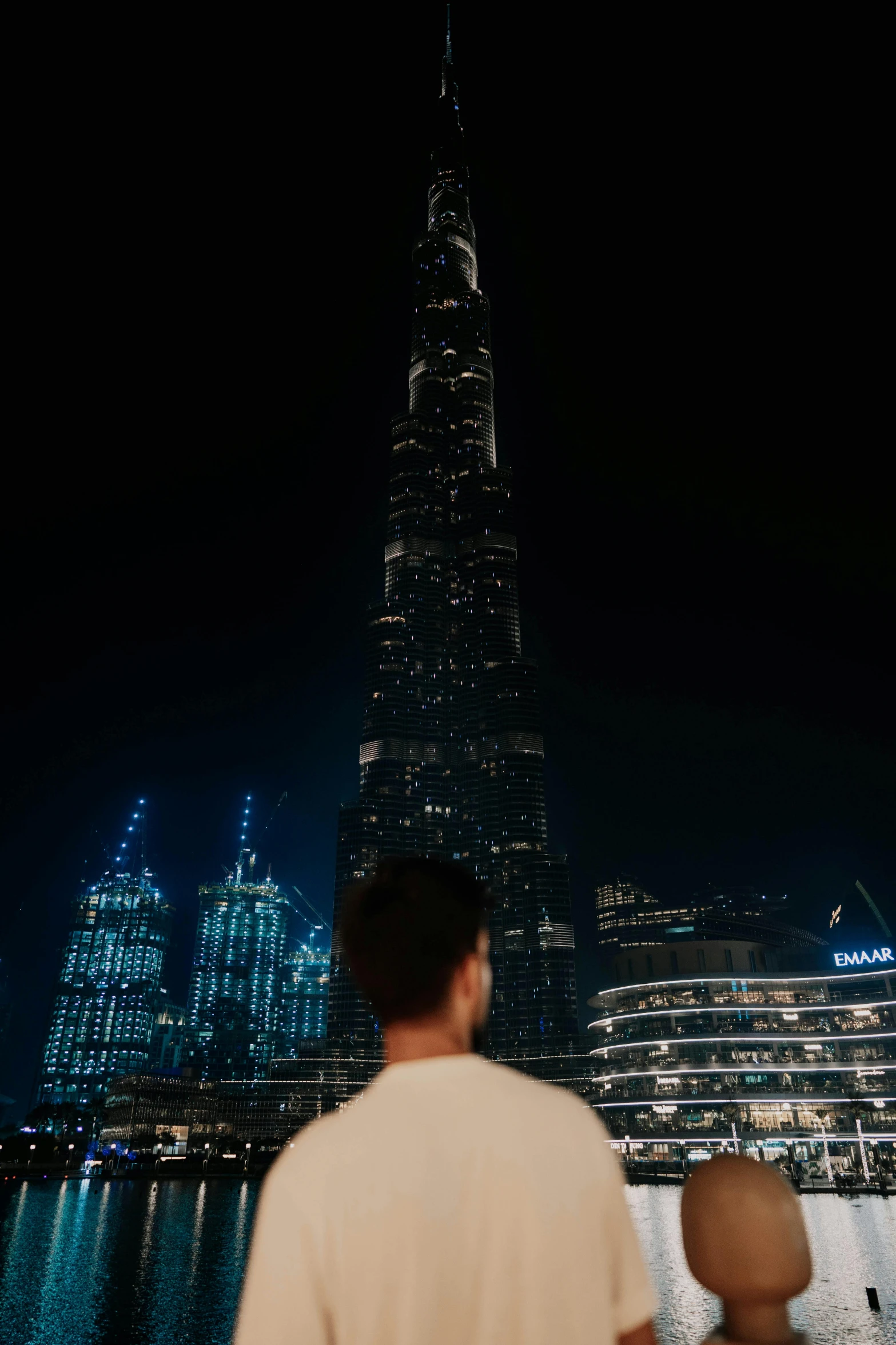 a man with a baby looking at a big building in the night