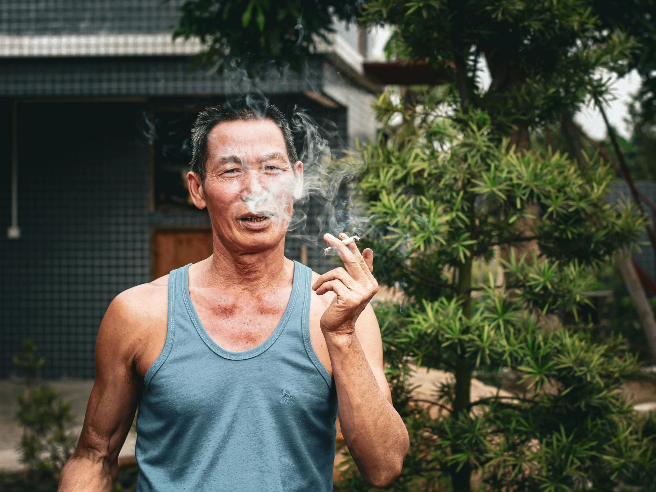 an old man smoking a cigarette in his backyard