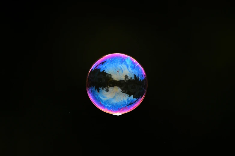 the sky and trees are reflected in an unusual, blue orb